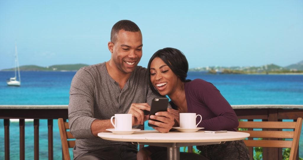 Cruise Line Apps: Couple on honeymoon sitting at restaurant with ocean view drinking coffee