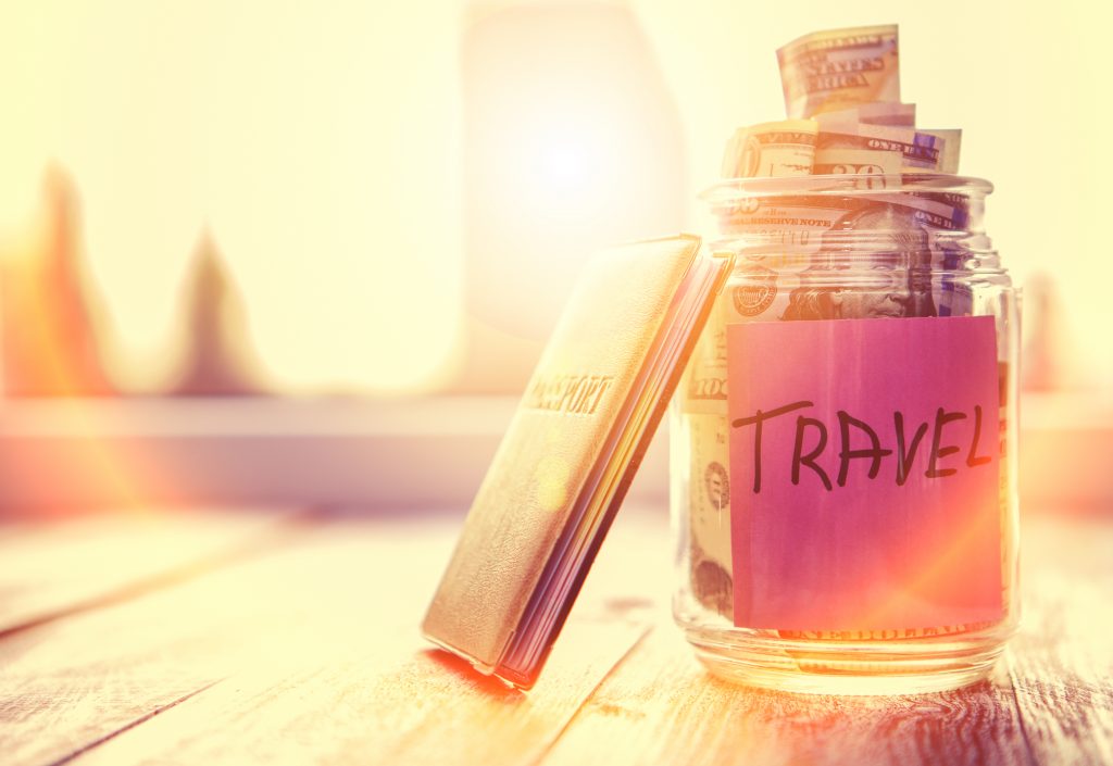 A glass jar with a note that says travel.  It is filled with money and has a passport leaning on it to show cruise vacation budget.