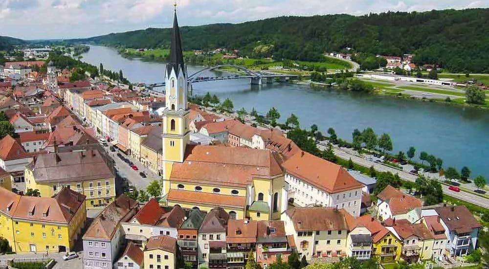 Aerial view of Vilshofen, Germany, showcasing its charming Bavarian architecture, St. John’s Church, and the Danube River winding through the picturesque town.