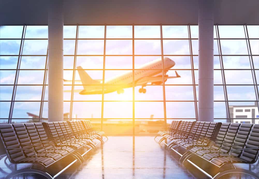 Modern airport terminal with empty seating and a plane taking off at sunrise, symbolizing the start of an international travel adventure.